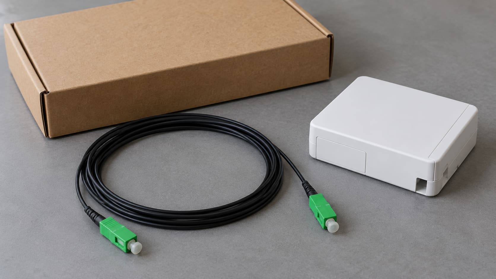 Pre-terminated drop cable with capped green connectors beside a household installation kit