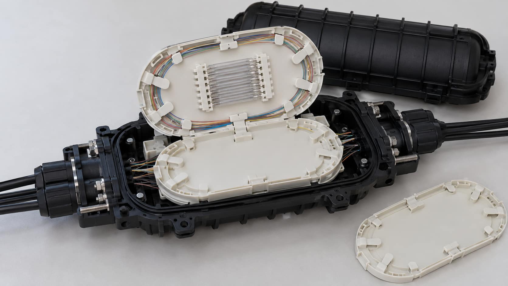 Illustrative closure trays with fiber routing guides and a spare tray